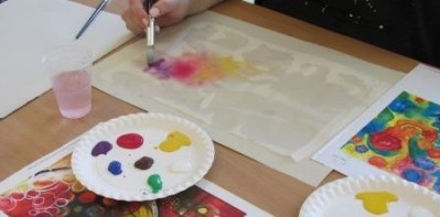 Image shows a close up of someone painting using watercolours.